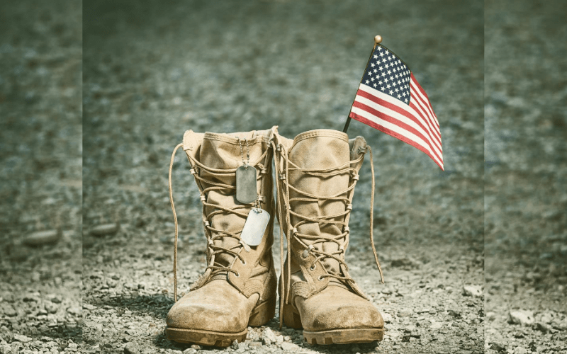 a pair of military desert boots with dog tags and an American flag